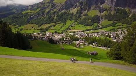 Grass-plain-in-the-swiss-alps,-with-a-village-downhill