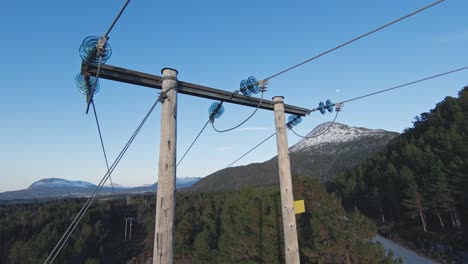 Wooden-high-voltage-power-line-top-in-majestic-Norway-landscape,-aerial-orbit-FPV-view