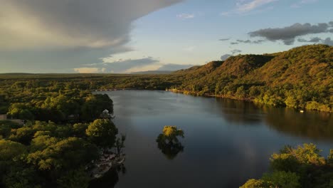 Lake-surrounded-by-green-hills-at-sunset,-Cordoba-in-Argentina