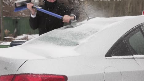 A-Man-Forcibly-Scraping-The-Ice-Frost-Formed-At-The-Rear-Windshield-Of-His-Car---Close-Up-Shot