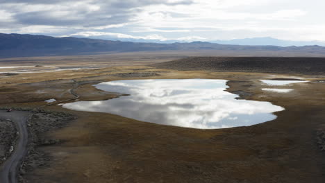 Small-lake-in-the-middle-of-a-desert-landscape-reflecting-the-clouds-in-the-sky