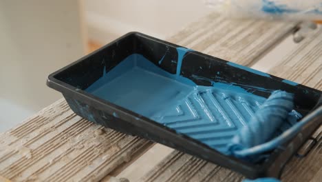 Dipping-the-paint-roller-into-blue-paint-in-plastic-tray