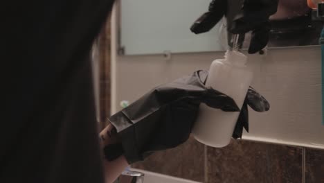 Eine-Person-Mit-Schwarzen-Handschuhen-Hat-Das-Haarbleichpulver-Zum-Mischen-Und-Auftragen-In-Toronto,-Kanada,-Gründlich-In-Den-Flaschenbehälter-Gegeben---Nahaufnahme
