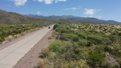 Car-appearing-driving-on-long-and-lonely-road-in-American-arid-place