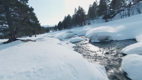 Majestic-frosty-winter-river-in-Norway-snowy-landscape,-FPV-aerial-view