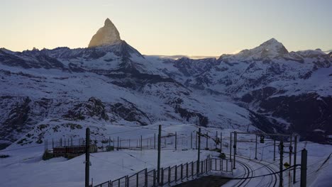 Gornergrat-mountain-railway-train-moves-to-its-final-stop-at-Gornergrat-with-impressive-views-of-the-Matterhorn-mountain-in-the-background-at-sunset