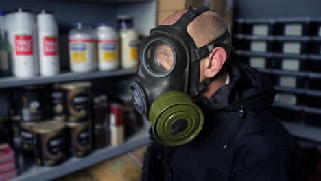 Doomsday-prepper-sitting-in-a-fallout-bunker-wearing-a-gas-mask-and-holding-a-submachine-gun