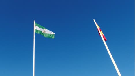 Andalusische-Und-Spanische-Flagge-Auf-Der-Stange-Vor-Blauem-Himmel