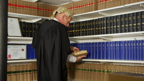 Ein-Richter-Oder-Rechtsanwalt-In-Einer-Juristischen-Bibliothek-Auf-Einer-Leiter,-Die-Nach-Einem-Buch-Greift