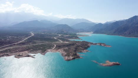Panoramic-drone-view-of-turquoise-blue-water-full-reservoir-in-mountains