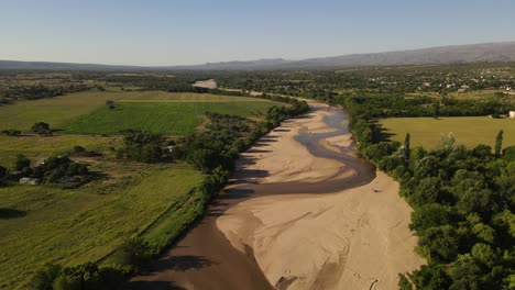 Aerial-view-of-sandy-river-and-drought-surrounded-by-green-landscape-during-hot-summer-in-Argentina