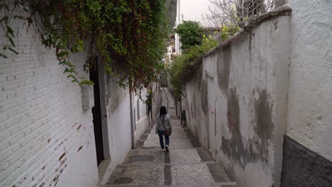 Back-of-female-walking-through-narrow,-seedy-alley