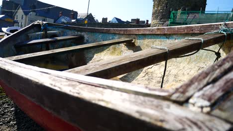 Empty-weathered-wooden-small-fishing-boat-sitting-on-Welsh-harbour-town-beach