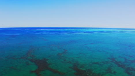 fly-over-with-a-drone-above-a-beautiful-gigantic-blue-lagoon-during-a-beautiful-day-with-no-cloud-in-the-sky