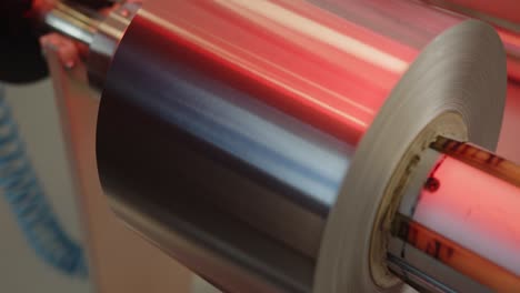 A-big-roll-of-aluminum-foil-on-a-feeder-of-the-cutting-machine---boom-down-close-up-shot