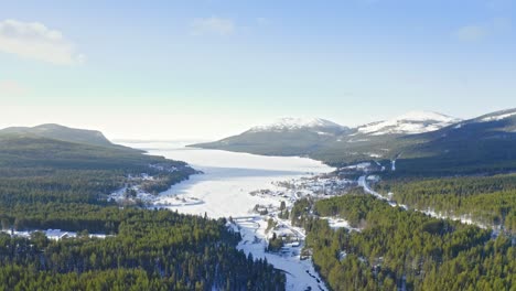 Drone-Flight-Above-Woodland-Valley-And-Snowcapped-Mountains-In-Winter