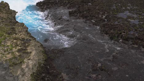 Waves-crashing-on-the-rocky-reef-in-slow-motion,-creating-a-beautiful-foam-pattern-during-the-day