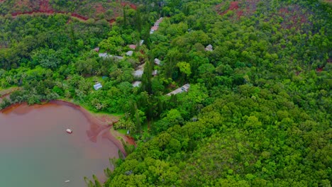 Drone-shot-flying-backward-above-a-little-village-lost-in-the-tropical-wood-near-the-sea