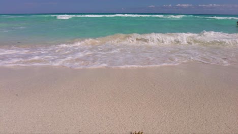 Close-up-of-the-waves-at-the-beach-in-Cancun-Mexico-with-the-blue-and-turquoise-caribbean-sea-in-the-back