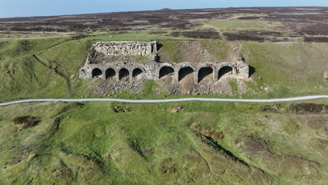 Rosedale-Abbey-Iron-Calcining-Kilns,-Aerial-Footage,-North-York-moors-National-Park,-Pull-back-from-Kilns-with-elevation