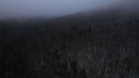 Aerial-drone-video-footage-of-nightfall-in-the-snowy,-foggy,-magical-Appalachian-mountains-during-winter,-in-the-Catskill-Mountains-sub-range