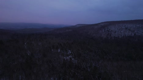 Aerial-drone-video-footage-of-nightfall-in-the-snowy-Appalachian-mountains-during-winter,-in-the-Catskill-Mountains-sub-range