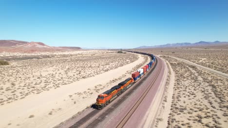 A-freight-train-rolling-down-the-track-in-a-desert-landscape---aerial-view-of-the-engine-pulling-cars-that-disappear-into-the-distance