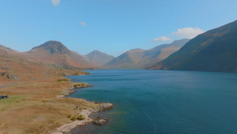WASTWATER-WASDALE-HEAD-Lake-District-Unesco-National-Park,-Aerial-Sunrise-pull-back-along-lake-with-mountains