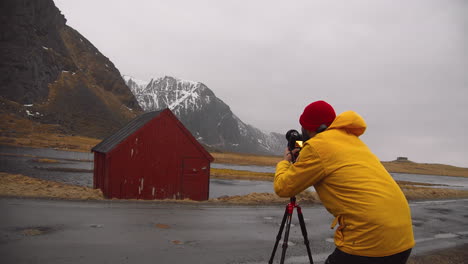 Fotógrafo-Tomando-Fotos-De-Cabaña-Roja-Con-Paisaje-Montañoso-En-Noruega