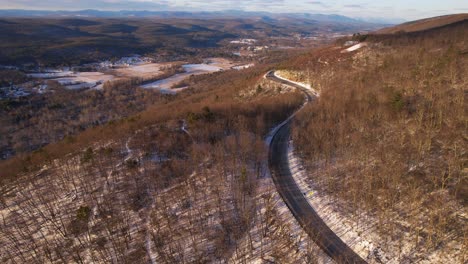 Aerial-drone-footage-of-a-beautiful-snowy-scenic-highway-in-the-Appalachian-mountains-during-winter-at-sunset-with-beautiful-light