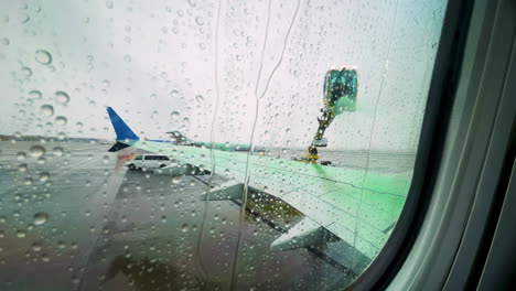 Window-Seat-POV-As-Airplane-Has-Wing-Sprayed-With-Green-De-Icing-Fluid
