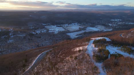 Aerial-drone-footage-of-a-beautiful,-colorful-sunset-of-the-snowy-Appalachian-mountains-during-winter