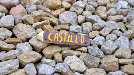 Wooden-Arrow-Sign-With-"Castillo"-Word-On-The-Pile-Of-Rocks