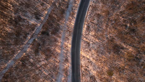 Aerial-drone-footage-of-a-Beautiful-Road-through-a-snowy-winter-forest-in-the-Appalachian-mountains-during-winter-in-New-York's-Hudson-Valley-in-the-Catskill-Mountains-sub-range