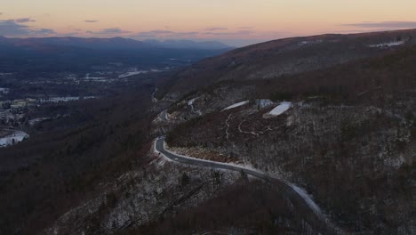 Aerial-drone-footage-of-a-beautiful-snowy-scenic-highway-in-the-Appalachian-mountains-during-winter-at-sunset-with-beautiful-light