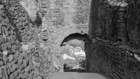 Black-and-white-shot-of-the-remains-of-an-old-entrance-gate-of-a-medieval-castle-in-Cervera-del-Maestre,-Castellon-province,-Spain