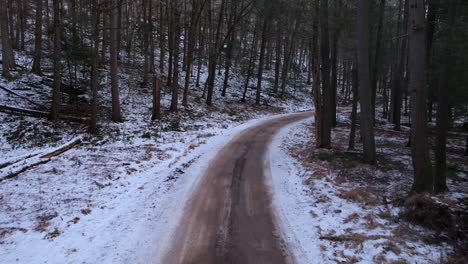 Smooth-drone-footage-of-a-beautiful-road-through-a-snowy-winter-forest-in-the-Appalachian-mountains-during-winter-in-New-York's-Hudson-Valley-in-the-Catskill-Mountains-sub-range