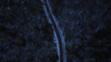 Smooth-nighttime-drone-footage-of-a-beautiful-road-through-a-snowy-winter-forest-in-the-Appalachian-mountains-during-winter-in-New-York's-Hudson-Valley-in-the-Catskill-Mountains-sub-range