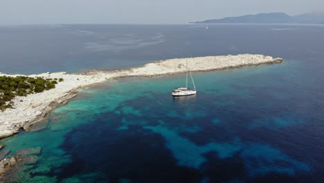A-Lone-Boat-Anchored-In-the-Shallow-Waters-of-Paralia-Emplisi-Beach-in-Erisos,-Greece---Orbiting-Aerial-Shot