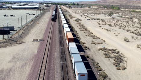 Aerial-Drone-Following-Moving-Freight-Trains-In-Barstow-Desert-In-The-USA
