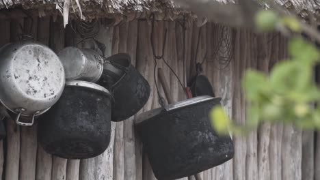 Empty-Old-Black-Iron-Cooking-Pots-And-Cauldrons-Hanging-On-A-Wooden-Log-Wall-In-A-Native-House-In-Mayan-Village-In-Mexico