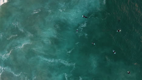 Happy-Surfers-Paddling-And-Gliding-Through-Turquoise-Blue-Waters-At-Llandudno-Beach,-Cape-Town-In-South-Africa