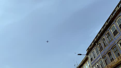 low-angle-view-of-airplane-flying-over-skyscrapers,-Porto-Portugal