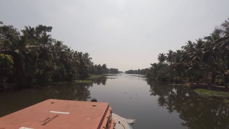 Navigable-canal-of-Alappuzha-or-Alleppey-seen-from-bow-of-boat-in-movement,-India