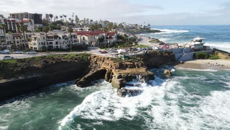 4K-aerial-of-a-Drone-pulling-back-from-the-shore-of-La-Jolla-beach-in-California-with-waves-splashing-on-the-rocks-on-a-sunny-day
