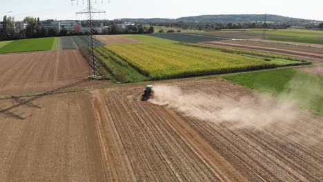 Aerial-shot-behind-a-tractor-making-dust-on-a-windy-field
