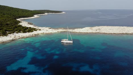 White-Boat-Anchored-Near-The-Pebble-Beach-Of-Emplisi-In-Kefalonia-Island---Aerial-shot