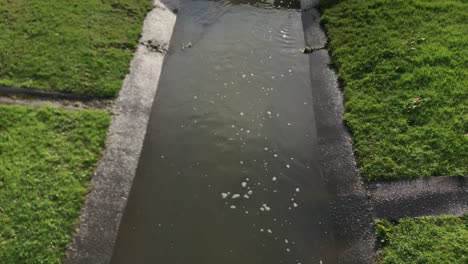 Regenwasser,-Das-Tagsüber-In-Einem-Abwasserkanal-Unter-Einem-Abflussrohr-In-Auckland,-Neuseeland,-Fließt