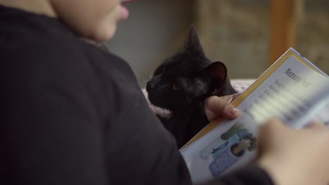 A-little-boy-reads-from-a-children's-book-while-his-cat-listens-carefully-sitting-nearby