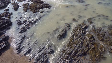 An-Der-Küste-Von-Mid-Wales-Umspülen-Wellen-Vertikale-Geschichtete-Felsen-Mit-Seetang